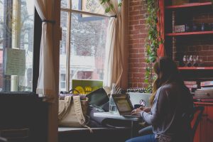 a girl working on her laptop facing a window