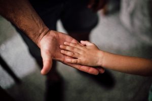 a man's hand holding a child's hand