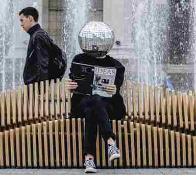 man reading magazine on bench