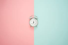 an alarm clock, with the background of pink and teal colors, evenly split between them.
