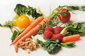 Assorted fresh produce on white background: apples, oranges, bananas, carrots, tomatoes, cucumbers, and more.