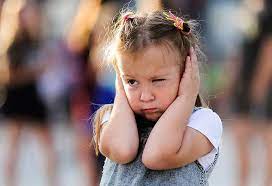 a child in a faded out background holding both of her hands against her ears, blocking out any potential noise.