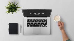 A person's hands holding a cup of coffee and a notebook on a desk, ready for a productive day.