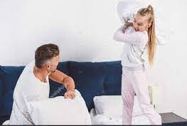 father and daughter doing a pillow fight