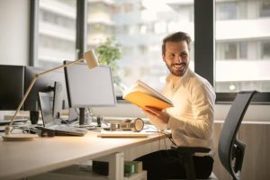 A man sitting at a desk, engrossed in a book, focused and absorbed in his reading.