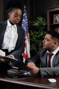 A man and woman in business attire engaged in a conversation, possibly discussing work-related matters.