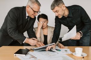 Three business people analyzing documents and discussing business strategies.