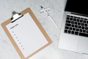 A laptop, clipboard, and pen on a marble table, creating a professional workspace.