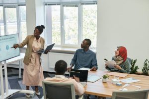 A team brainstorming session in progress, with people gathered around a whiteboard in a meeting room.