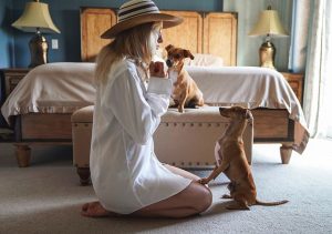  Woman in white shirt and hat sitting on floor with two dogs