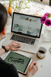 1. Person typing on a laptop with a blank screen, surrounded by notebooks and pens, engaging in creative writing.