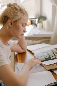 A woman engrossed in a book, sitting at a table, lost in the world of words and imagination.