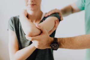 Man assisting woman with her arm.