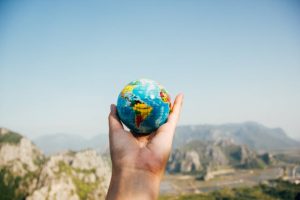 A person holding a small earth globe in their hand.