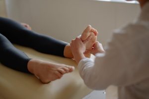 A woman receiving a foot massage from a doctor in a professional setting.