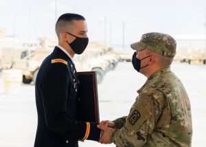 A soldier in uniform shaking hands with another soldier, symbolizing camaraderie and unity.