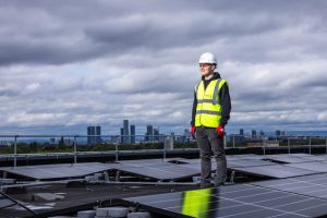 A man in a hard hat inspecting solar panels.