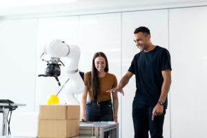 A man and woman standing in front of a robot, showcasing human interaction with advanced technology.